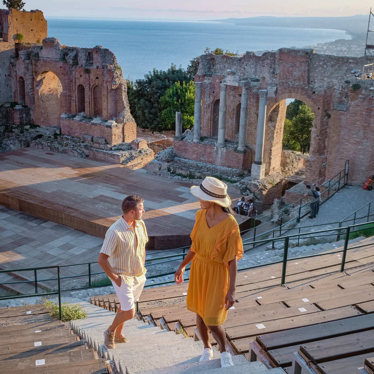 A Couple Of Tourists Photographed In The Ancient Theater Of Taormina, Sicily, Italy