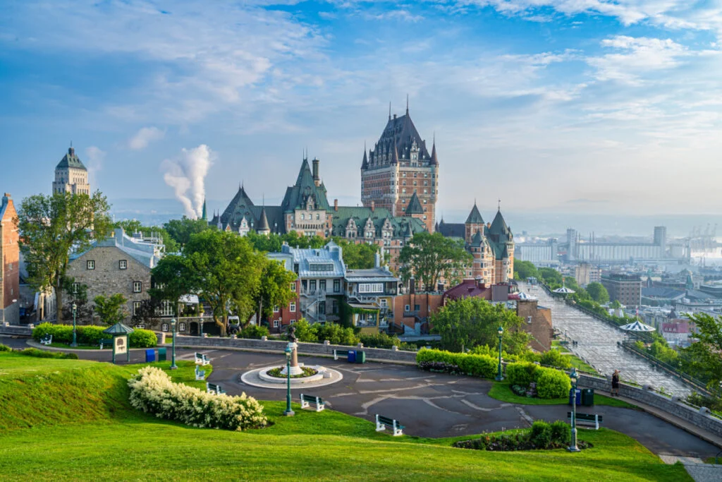 A scenic high-angle view captures the iconic Chateau Frontenac in Quebec City, Canada, under a bright blue sky