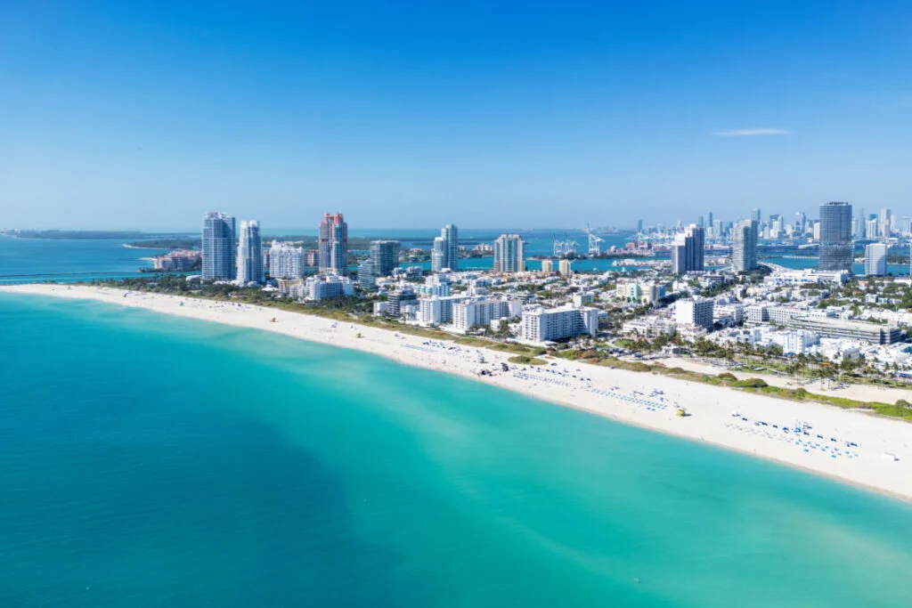 Miami Beach on blue sky. Skyline aerial view. Miami city. Tropical Miami scene. Miami district sky view. Famous oceanfront. Panoramic-coastline. South beach panorama view. Summer holiday vibes.