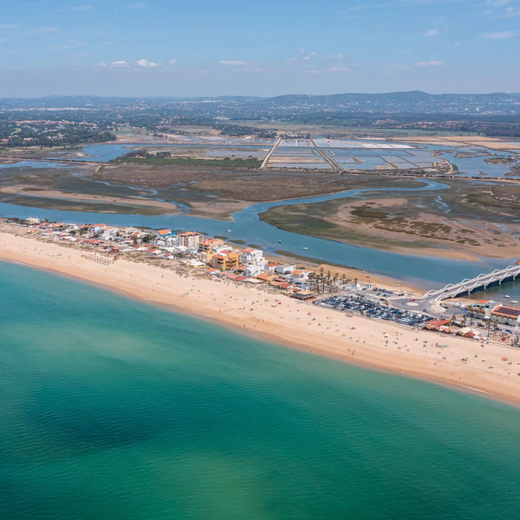 Praia de Faro along the coast in Ria Formosa, Algarve, Portugal, captured from above with clear water and land outlines on a sunny day