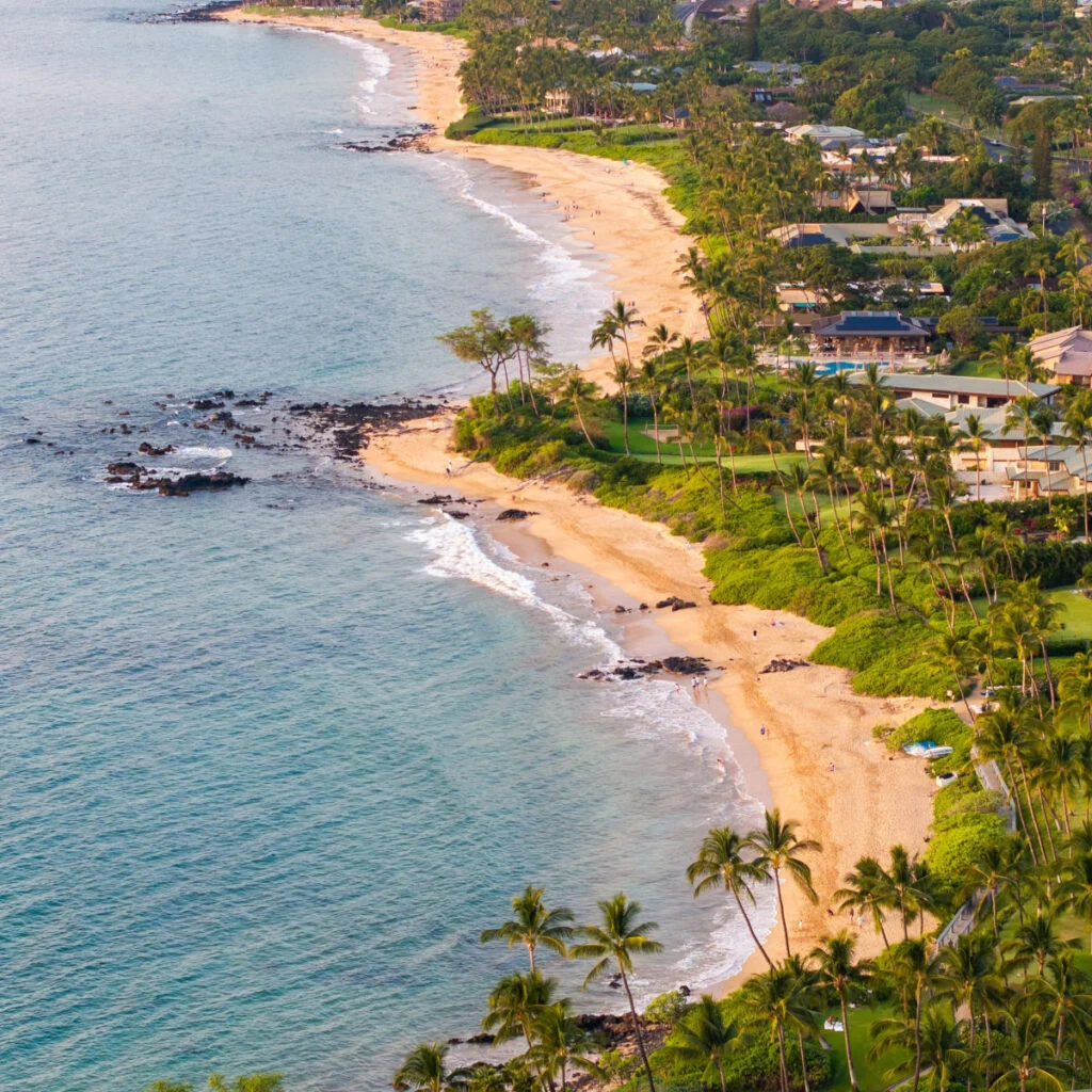 Panoramic aerial view of Wailea Beach Path, resorts, and vacation homes along coastal beachfront landscape in Wailea-Makena Maui Hawaii during golden hour sunset